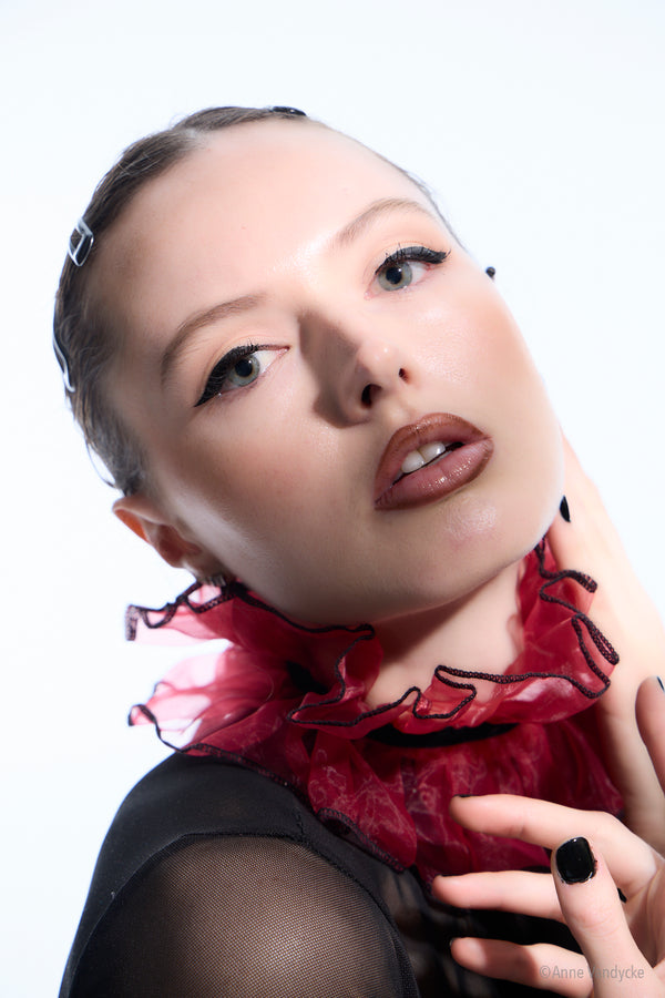 Woman wearing a red scarf with black accents on a white background. Studio photos by New York photographer, Anne Vandycke.