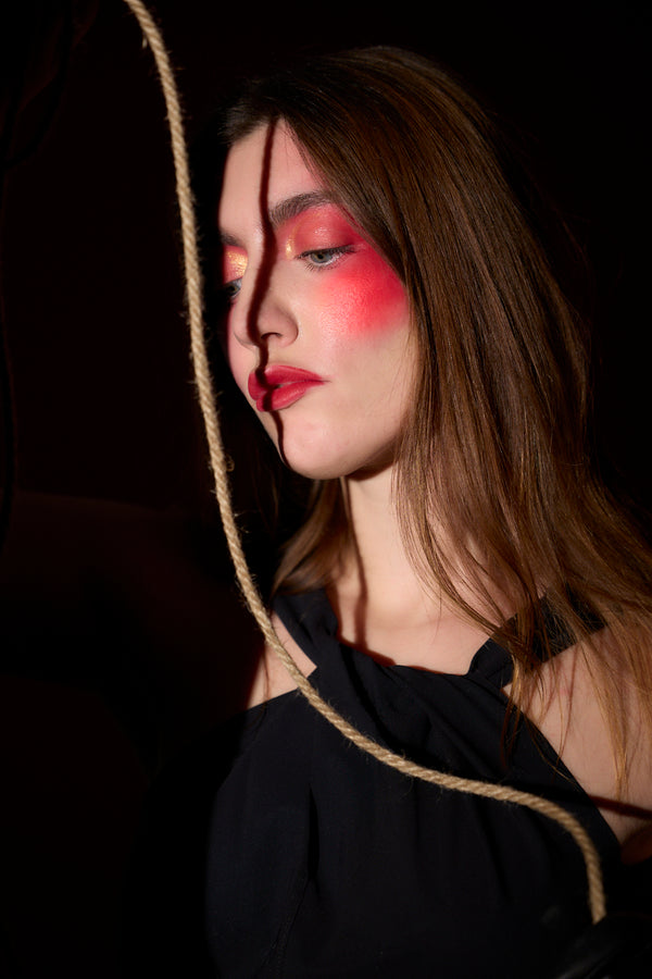 Woman in the dark wearing a black dress and holding a rope. Part of Anne Vandycke's series, "Couture & Canvas."
