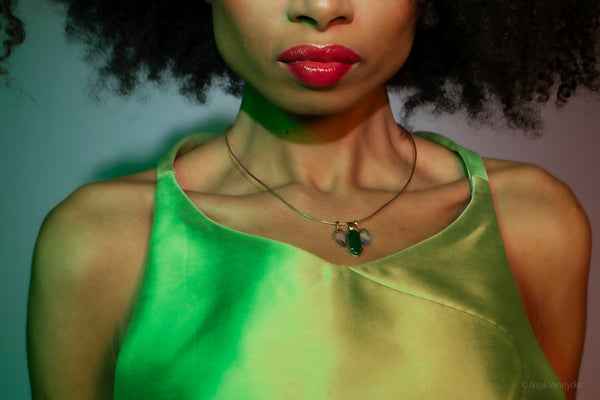 Woman wearing a green satin dress featuring a green pendent necklace. Photo by Anne Vandycke.