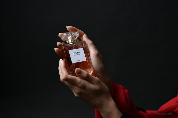 Hands holding a perfume bottle against a dark background. Photo ad by New York Photographer, Anne Vandycke.