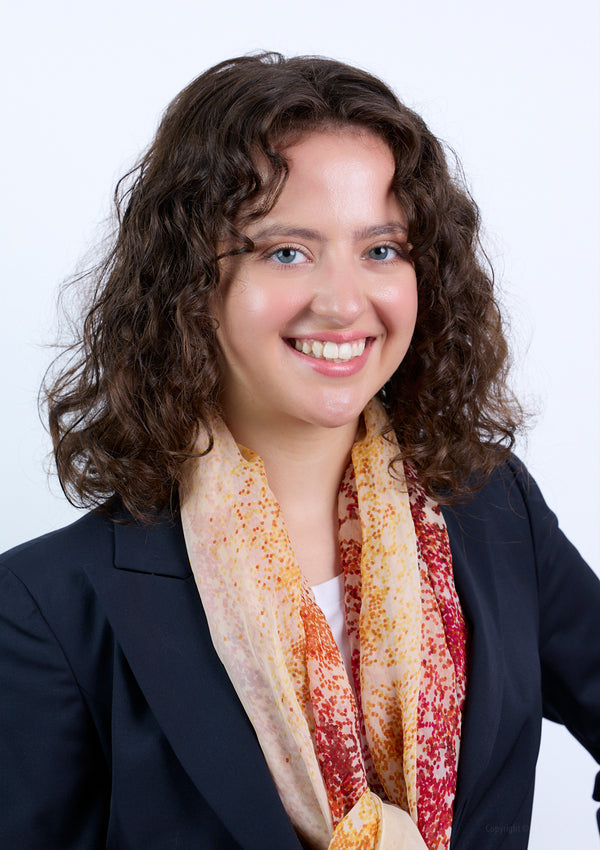 Woman wearing a dark blazer and colorful scarf against a white background. Headshot photography by New York City photographer, Anne Vandycke.