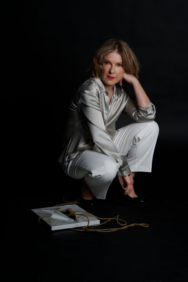 Artist, Anne Vandycke in silver outfit, posing next to her art piece, Resilience 3, the Art of transformation.