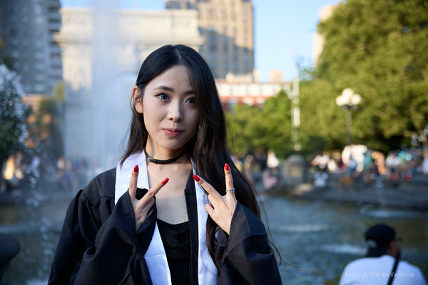 Woman posing outdoors with a fountain and cityscape in the background. Urban Photography by New York photographer, Anne Vandycke.