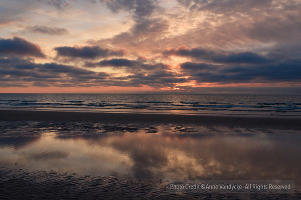 Sunset over a beach with reflected clouds on the water. Photo by Anne Vandycke, NYC Photographer.