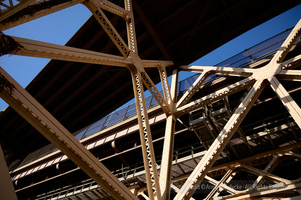 Close-up of a metal bridge structure with a clear blue sky in the background. Architecture photography by Anne Vandycke.