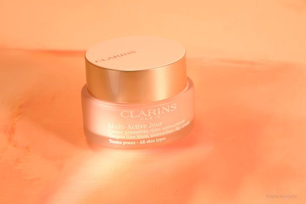 Clarins skincare product on a peach background. Photo styled and shot by Anne Vandycke.