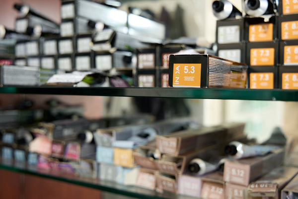 Shelf with various boxes of hair dye and products in a store setting. Hair Salon photoshoot by New York photographer, Anne Vandycke.