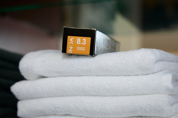 Spa photoshoot by Anne Vandycke. Box of hair dye on stack of white towels.