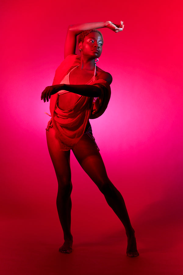 Dancer in a red outfit against a pink background. Studio photos by New York photographer, Anne Vandycke/Copyright 2026 ©Anne Vandycke, All rights reserved. 