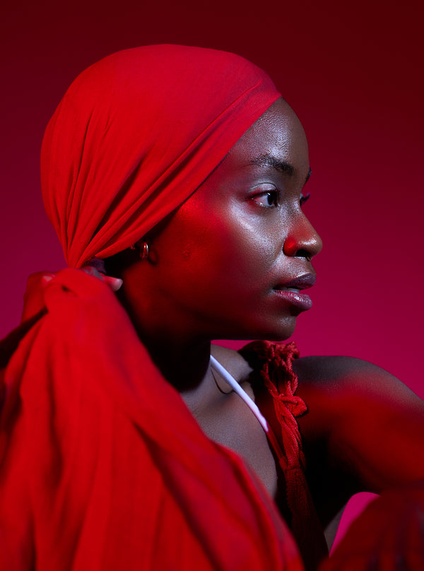 Woman wearing a red headscarf against a red background. Studio photos by New York photographer, Anne Vandycke/Copyright 2026 ©Anne Vandycke, All rights reserved. 