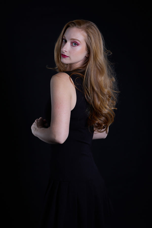 Woman in a black dress against a black background. Studio photos by New York photographer, Anne Vandycke/Copyright 2026 ©Anne Vandycke, All rights reserved. 