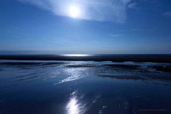 Sunlit beach with clear blue sky and water. Photo taken by New York City photographer, Anne Vandycke.