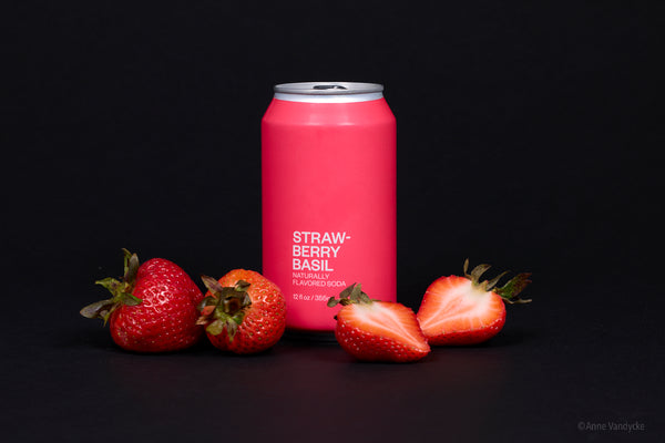 Pink can of strawberry basil flavored drink with strawberries on a black background. Photo taken by Anne Vandycke, NYC photographer.